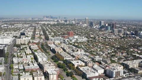 Aerial pullback shot of Beverly Hills shops, car traffic, buildings, LA skyline Stock Footage 272759345
