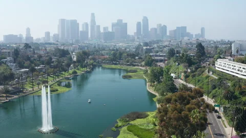Aerial pullback shot of Echo Park lake, fountains, trees, LA offices buildings Stock Footage 273836313