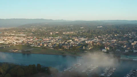 Aerial pullback shot of Eureka California during golden hour with fog and boats Stock Footage 200576681