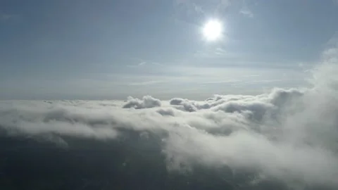 Aerial pullback shot high over the clouds with bright sun into the misty clouds Stock Footage 147899215