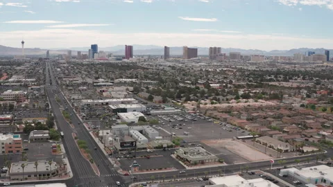 Aerial pullback shot  Las Vegas commercial stores and shops with city skyline Stock Footage 197655277