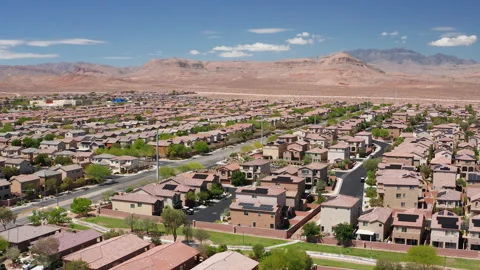 Aerial pullback shot of Las Vegas suburban desert homes with sandstone mountains Stock Footage 308819561