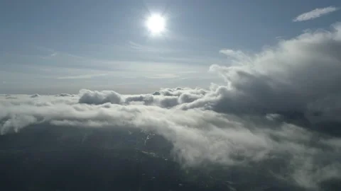 Aerial pullback shot over the clouds into the beautiful blue sky with bright sun Stock Footage 147900961