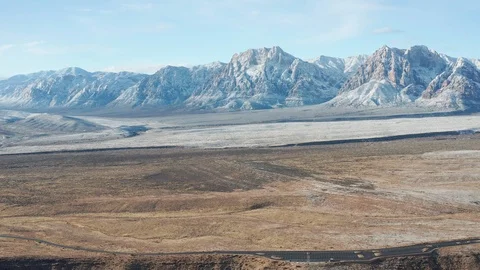 Aerial pullback shot of snow covered desert mountains, colorful sandstone cliffs Stock Footage 122056956