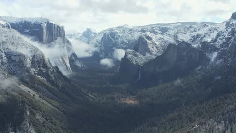 Aerial pullback shot of Yosemite mountains, waterfalls, and forest in winter Stock Footage 270843548