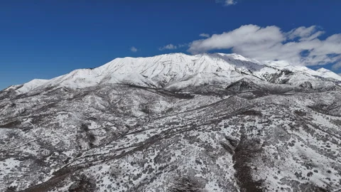 Aerial-Pullback-Snow covered mountain under blue sky-white clouds Stock Footage 267046179