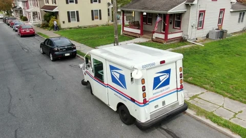 Aerial pullback of USPS truck, US Postal Service mail truck parked along Stock Footage 130567106
