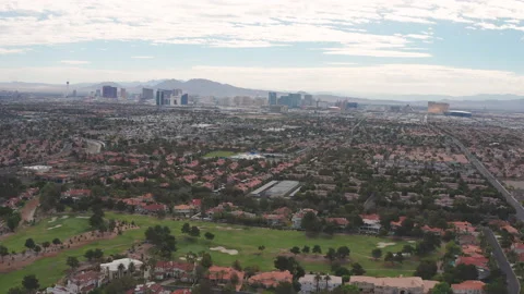 Aerial pullback view of gated Las Vegas community with city skyline strip view Stock Footage 197638963