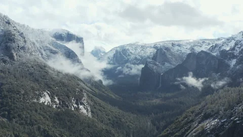 Aerial pullback view of Yosemite National Park covered in snow and clouds Stock Footage 270837281