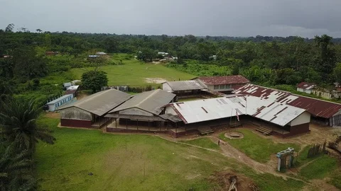 Aerial Pulling Away From Third World School with US or Liberian Flag on Pole Stock Footage 101624292