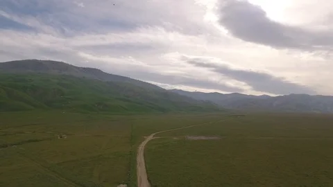 Aerial Pulling back from Hills over Green Field RAW 60fps Stock Footage 93116340
