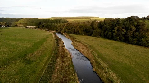 Aerial-Pulling back over clear mountain stream-green fields-English countryside Stock Footage 96300070