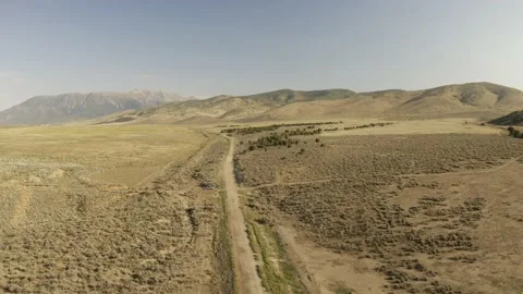 Aerial-Pulling back over desert dirt road through sagebrush flats Stock Footage 159511419