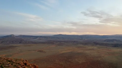 Aerial-Pulling back over rugged sandstone cliffs from view of distant valley Stock Footage 117621914