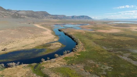 Aerial-Pulling back over runoff swollen stream in rural mountain valley Video stock 112361171
