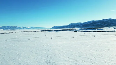 Aerial-Pulling back over snowy fields with distant snow covered mountains Stock Footage 238770439