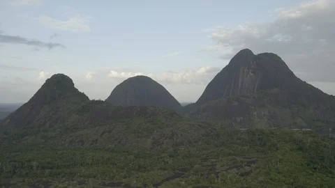 Aerial pulls back and ascends to reveal all of the Cerros de Mavecure at dawn Vídeos de archivo 100826627