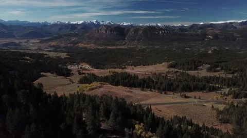 Aerial Pulls Back And Tilts Up Revealing Snow Capped Mountains Beyond Autumn Video stock 145821060