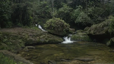 Aerial pulls back from the lush river outside the canopy to reveal Fin del Mundo 스톡 동영상 104884156
