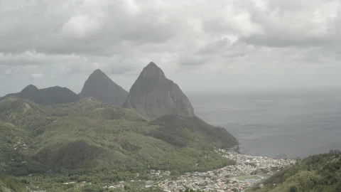 Aerial pulls back over hilltop in Saint Lucia with the Pitons in the distance 스톡 동영상 209470681