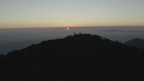 Aerial pulls back over Palomar mountain as the sun sets behind the clouds Stock-Footage 150804113