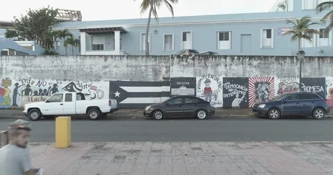 Aerial pulls back from the painted boardwalk to reveal the shoreline of San Juan 스톡 동영상 99498839