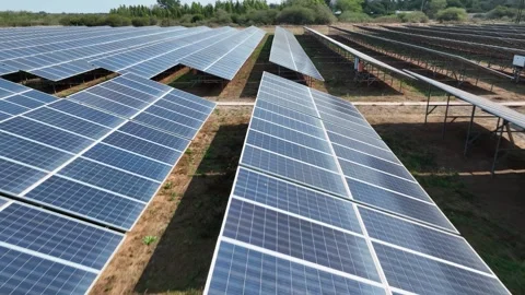 Aerial pulls back to reveal large solar panel array in rural landscape Vídeo Stock 345329689