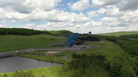 Aerial push in and tilt down showing coal trucks pulling into a coal elevator Stock Footage 133015691