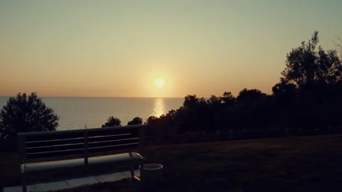 Aerial push-in drone shot of sunset above park bench Stock Footage 146984171