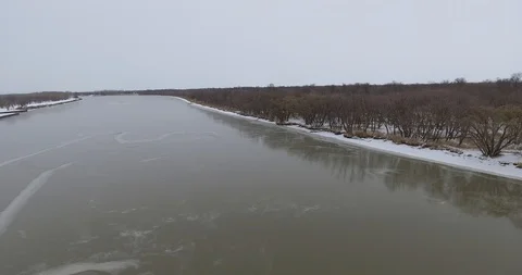 Aerial push over winter river, trees, houses in b/g Stock Footage 86297354