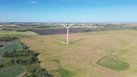 Aerial push-in shot of a large wind turbine in a vast field. Stock Footage 316637914