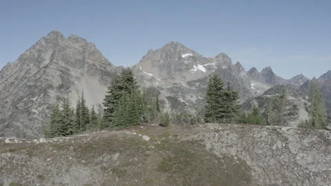Aerial pushes over ridge through trees to reveal mountains by Maple Loop Trail Stock Footage 345177717