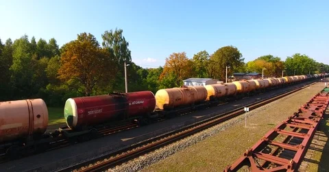 AERIAL railway: cargo train transporting wagons across the small local station Stock Footage