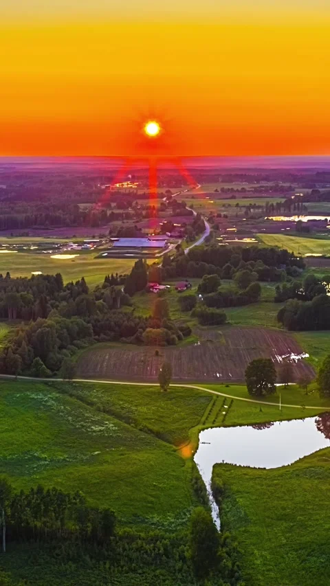 Aerial Red Sun Setting over Green Farmland, River and Farmhouses in Latvian 스톡 동영상 347972554