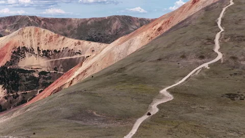 Aerial of remote dirt road through colorful mountain slopes in Colorado with UTV Vídeo Stock 343153297