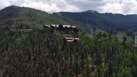 Aerial of resort complex nestled in forested mountains near Telluride Colorado Stock Footage 341999761