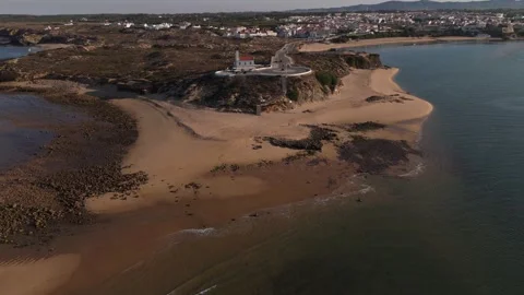Aerial reveal of Vila Nova de Milfontes lighthouse and beach at golden hour Stock Footage 346372984