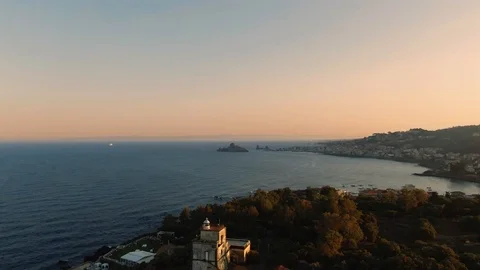 Aerial revealing view of a lighthouse at sunset in the East coast of Sicily Stock Footage 110803875