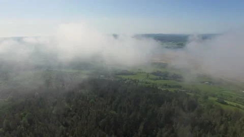 An aerial reverse flight through low clouds over a forested hill on Anglesey Stock Footage 234069970