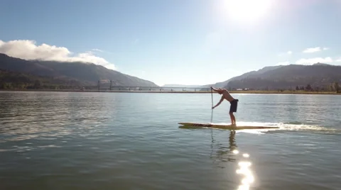 Aerial right to left move of SUP rider with hood river bridge in background. Stock Footage 68627118