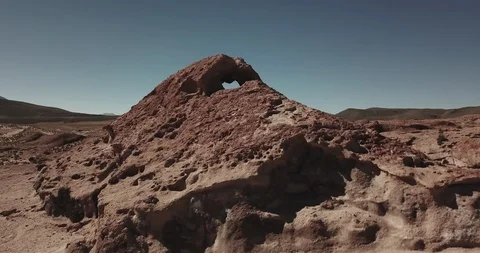 Aerial rises up over red rock to reveal snow capped volcano in the distance Stock-Footage 87510258