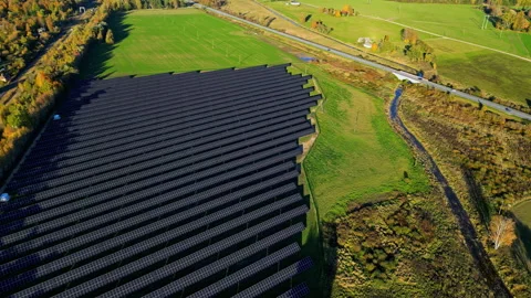 Aerial rising pullback reveal of solar panel array next to green pastures and Stock Footage 331930163