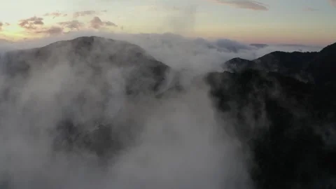 Aerial rising through clouds with mountain forest landscape on the horizon and Stock Footage 284249241