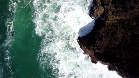 Aerial rising top down view of breaking waves along rocky ocean shore Stock Footage 79838730