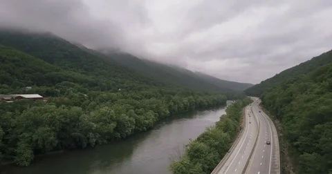 Aerial of River Cutting Through Misty Foggy Forest Mountains and Highway Stock Footage 77369062