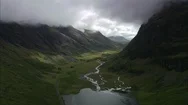 Aerial Of River Flowing Through The Mountain Ranges, Glencoe And Mountains Stock Footage