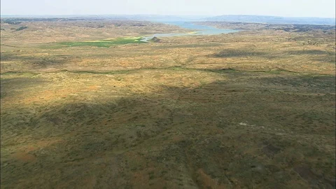 Aerial of river flowing through rolling hills covered with grass, Approaching Stock Footage 109459195
