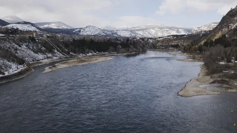 Aerial of river streaming through land with snowy mountains and forest, Canada Stock Footage 121587916