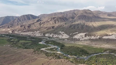 Aerial river valley below eroded mountains, Kok-Moinok Canyons, Kyrgyzstan Видео 347239916