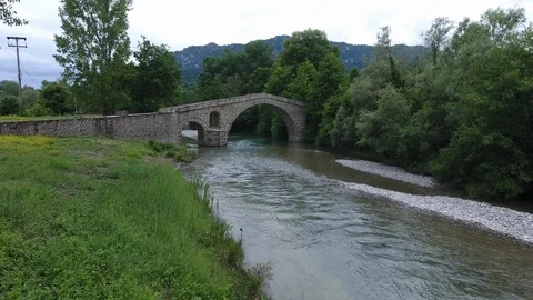 Aerial riverfront and bed flight over an old stonebridge Ziakas at Ven Stock Footage 98592966